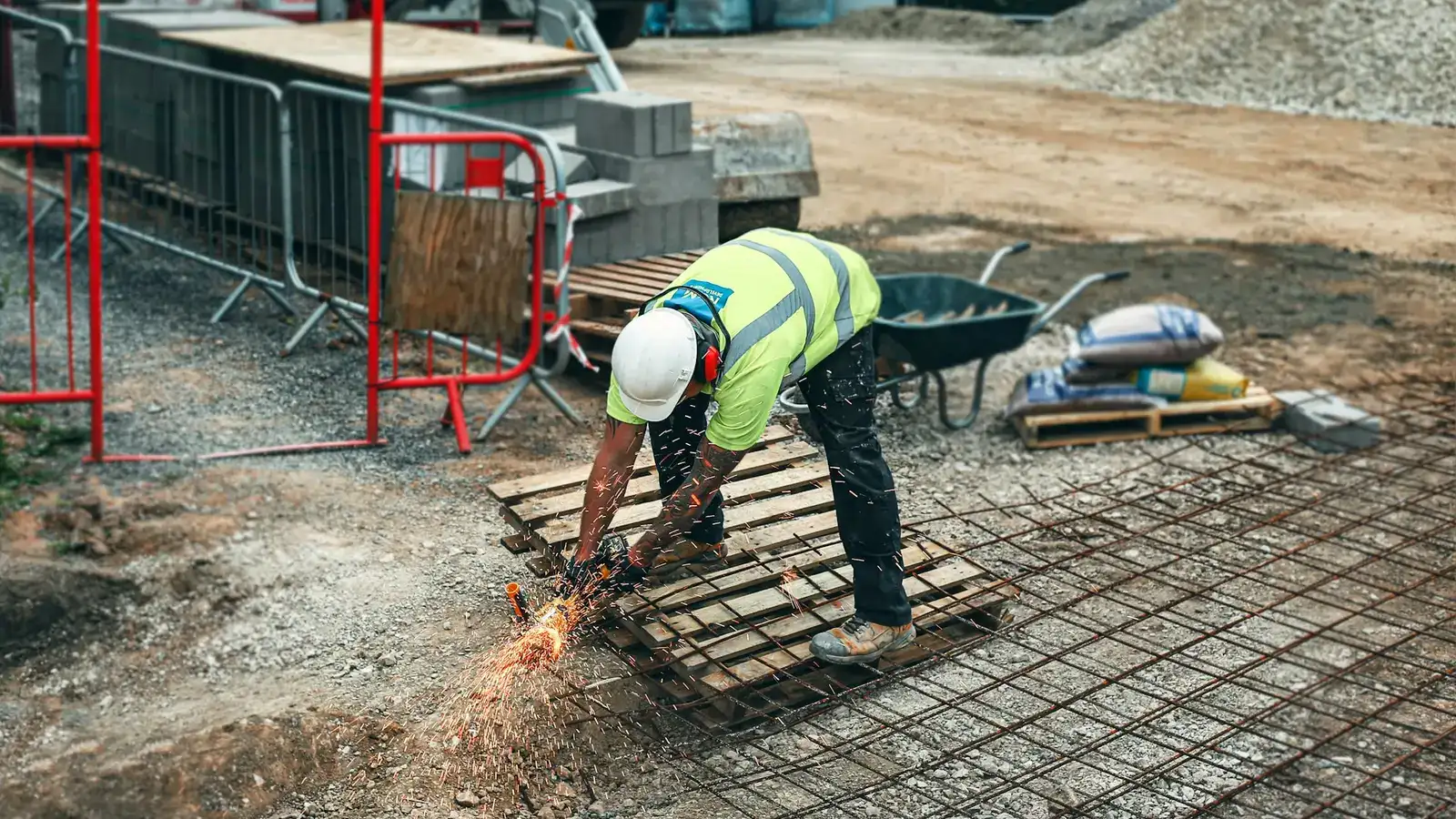 Ouvrier du BTP en train de meuler des armatures sur un chantier, appels d'offres travaux